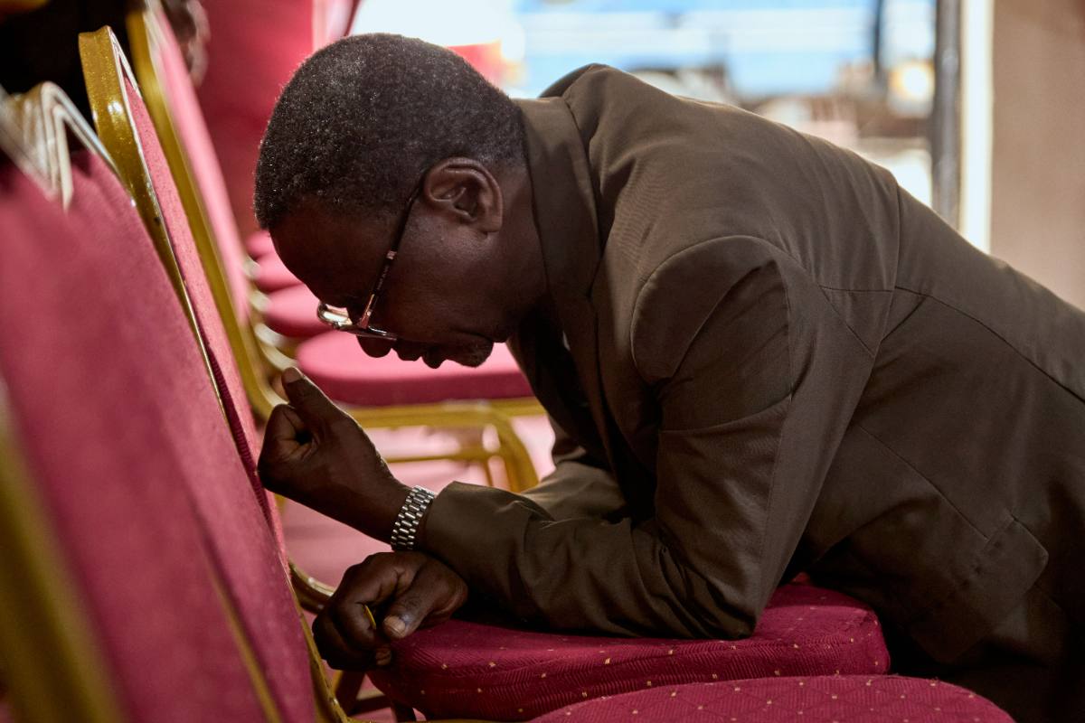 Man kneeling in quiet prayer with head bowed
