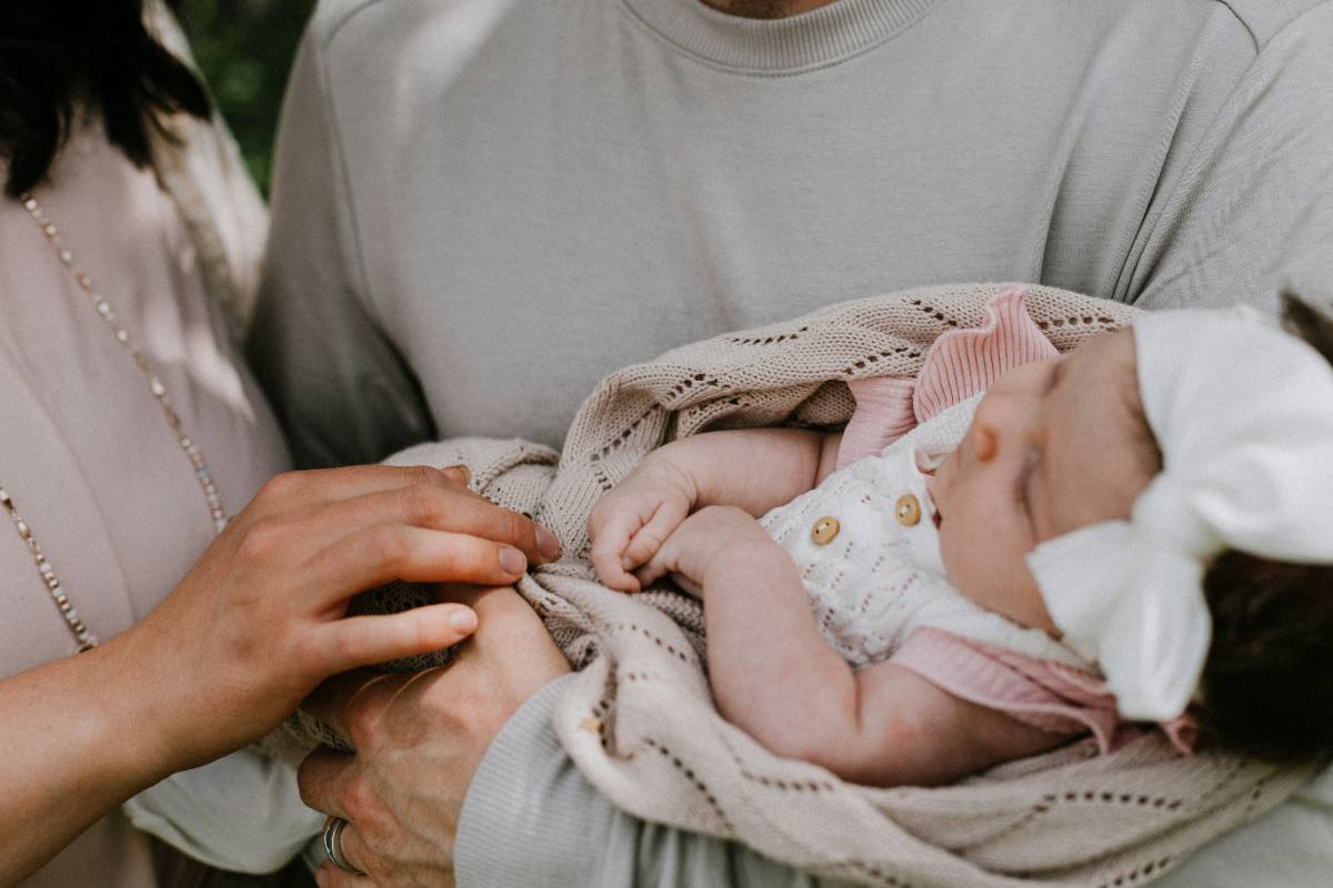 Parents gently holding their sleeping newborn daughter