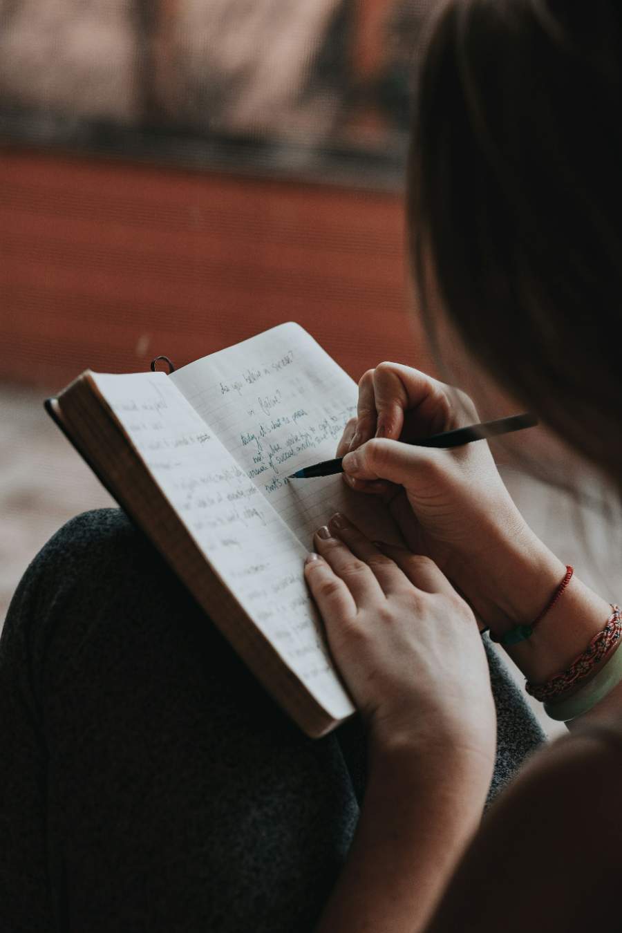 Woman writing quiet time reflections in a personal journal, part of a beginner's guided Bible journaling routine