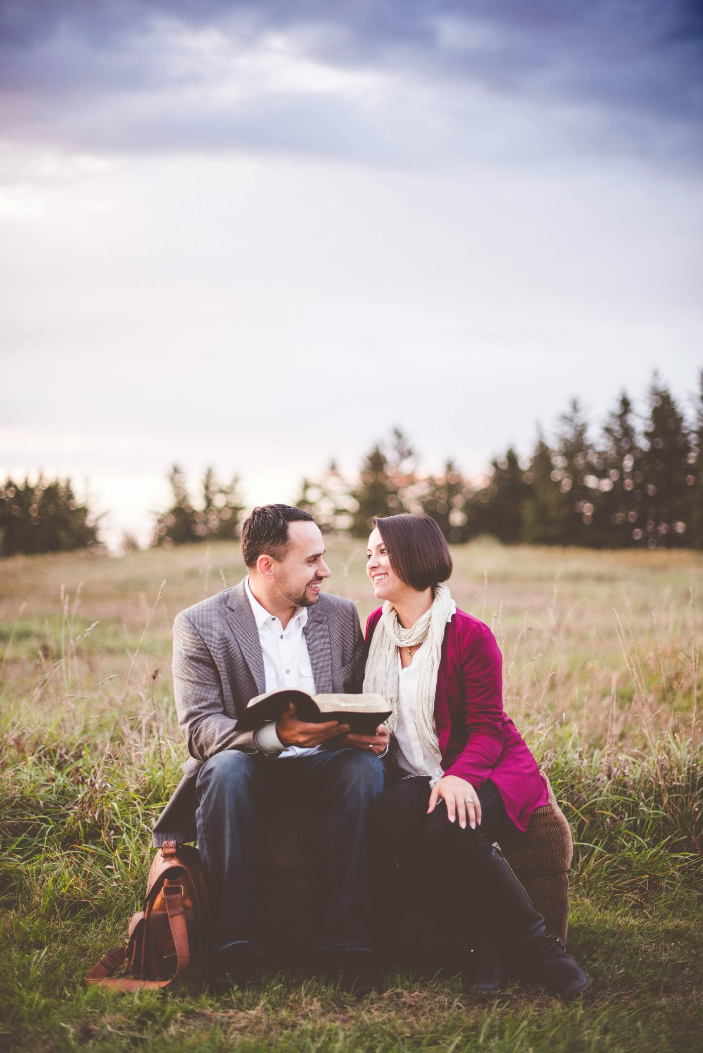 Engaged couple reading Scripture together outdoors