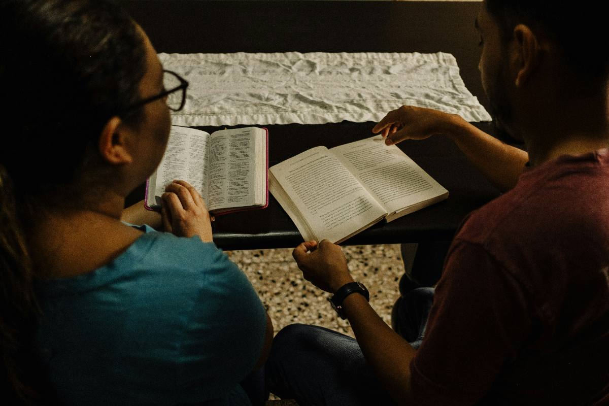 Two women praying together on a couch