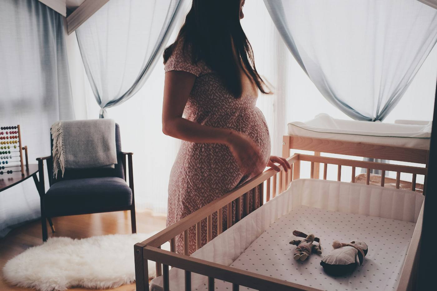 Pregnant woman standing beside a nursery crib